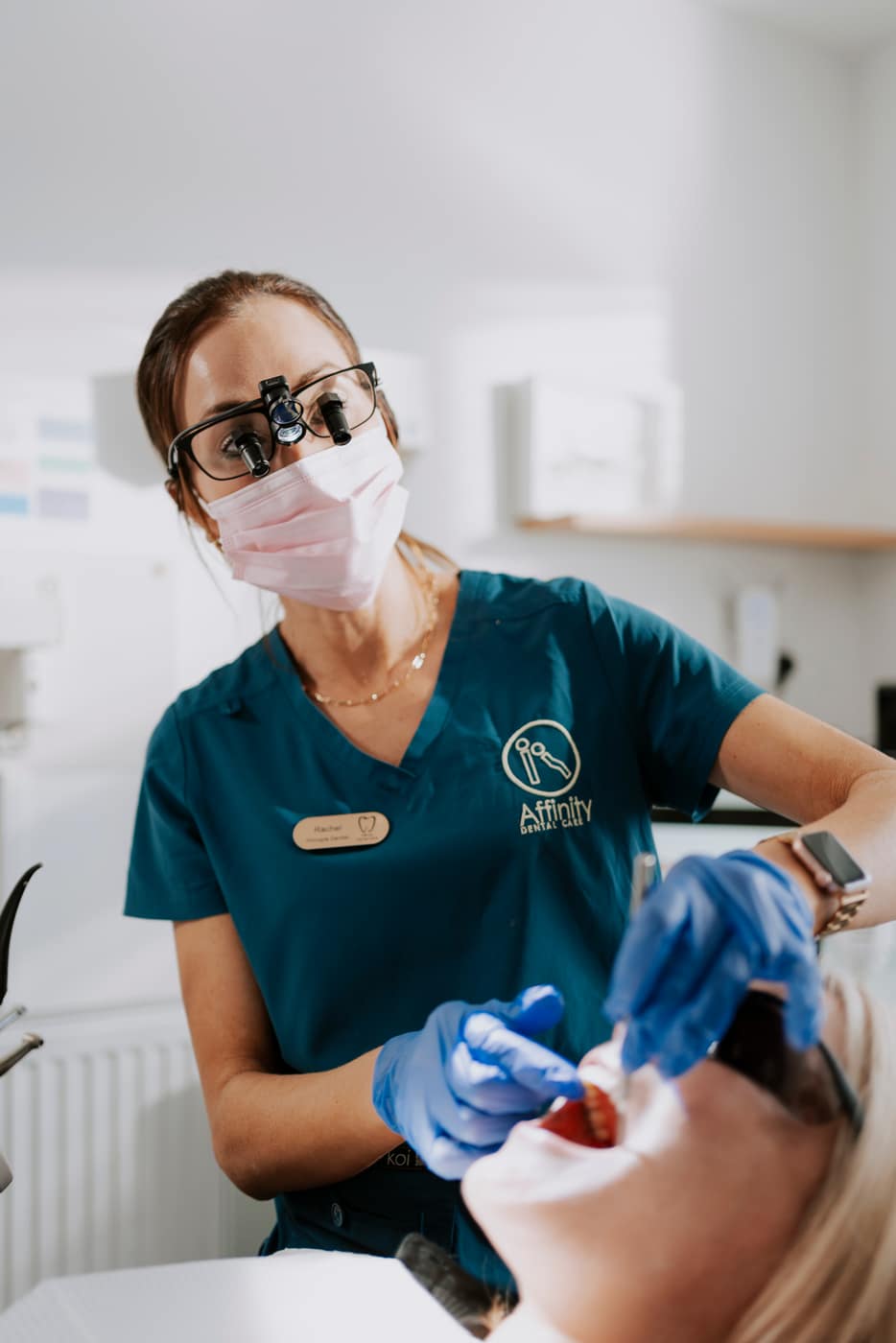 A dentist in magnifying loupes treating a patient